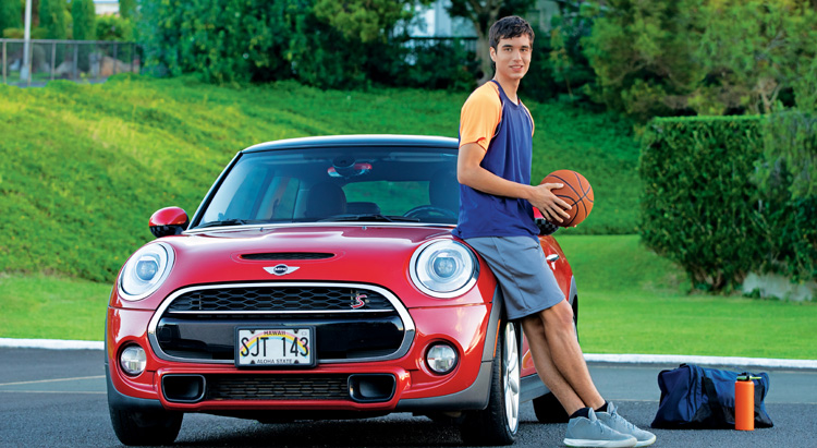man holding a basketball next to his car